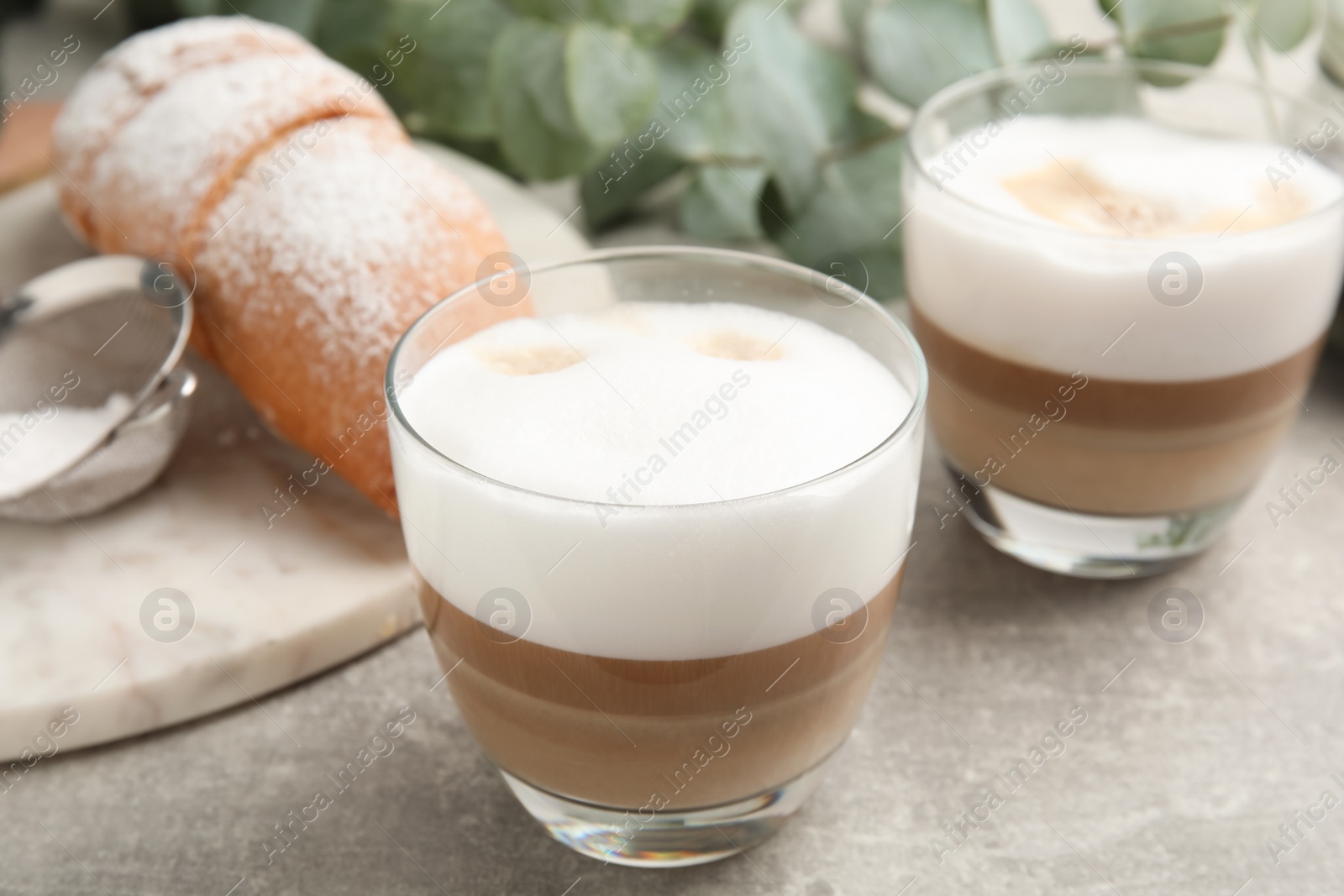 Photo of Delicious latte macchiato and croissant on light grey table