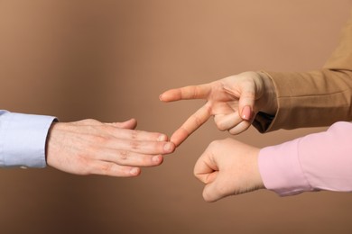 Photo of People playing rock, paper and scissors on brown background, closeup