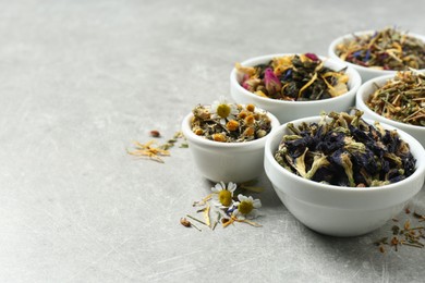 Photo of Different dry aromatic teas on light grey table, space for text