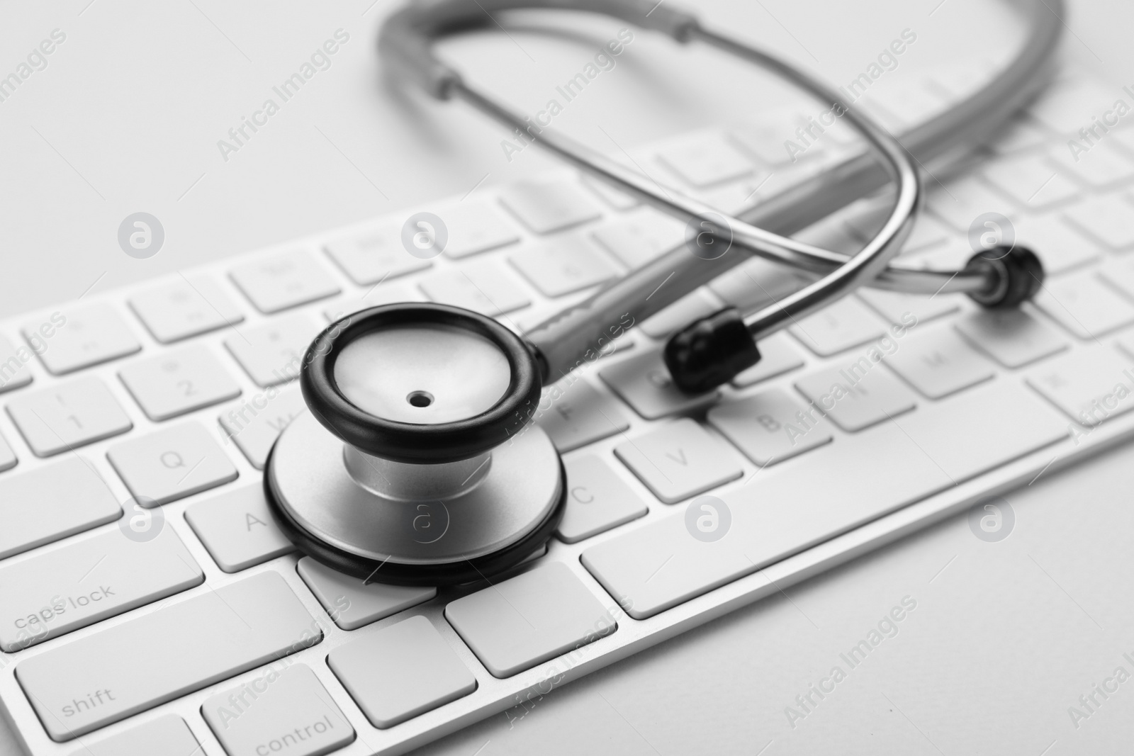 Photo of Keyboard and stethoscope on beige background, closeup