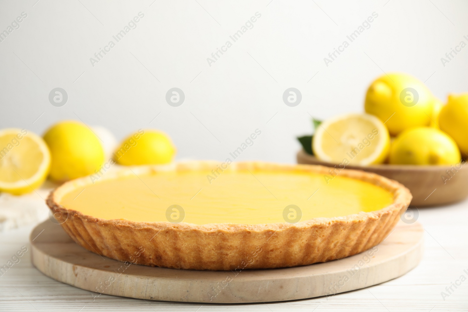 Photo of Delicious homemade lemon pie and fresh fruits on white wooden table, space for text
