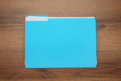 Turquoise file with documents on wooden table, top view