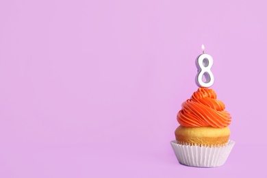 Photo of Birthday cupcake with number eight candle on violet background, space for text