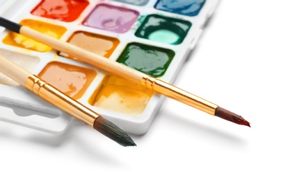 Photo of Brushes and plastic palette with colorful paints on white background