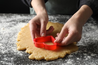 Photo of Shortcrust pastry. Woman making cookie with cutter at grey table, closeup