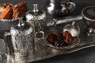 Photo of Tea, Turkish delight and date fruits served in vintage tea set on grey textured table