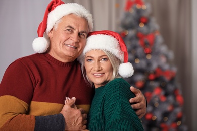 Happy mature couple in Santa hats at home. Christmas celebration