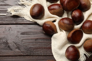 Photo of Sweet fresh edible chestnuts on wooden table, top view. Space for text