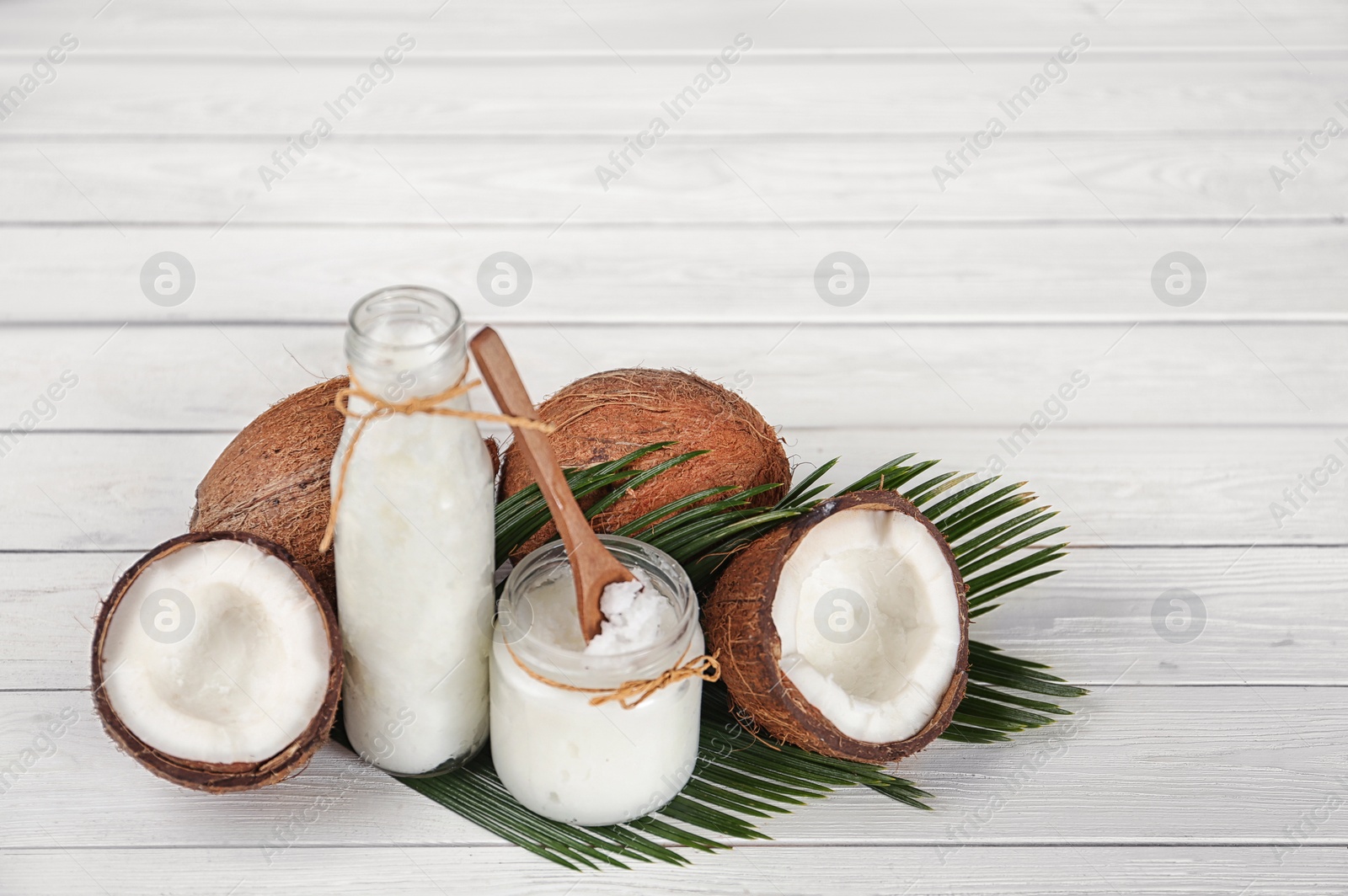 Photo of Composition  with fresh coconut oil on white wooden table. Cooking ingredient