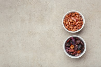 Bowls with different types of beans on light grey table, flat lay. Space for text