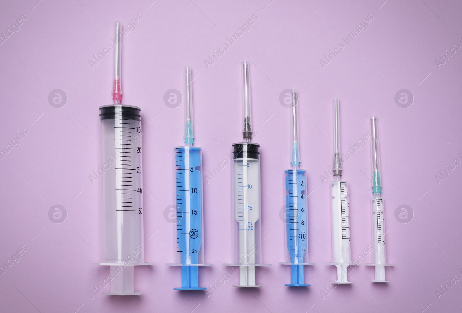 Photo of Disposable syringes with needles on violet background, flat lay