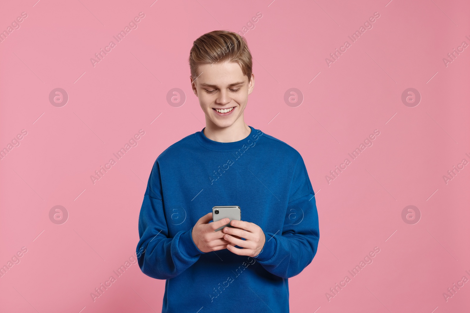 Photo of Teenage boy using smartphone on pink background