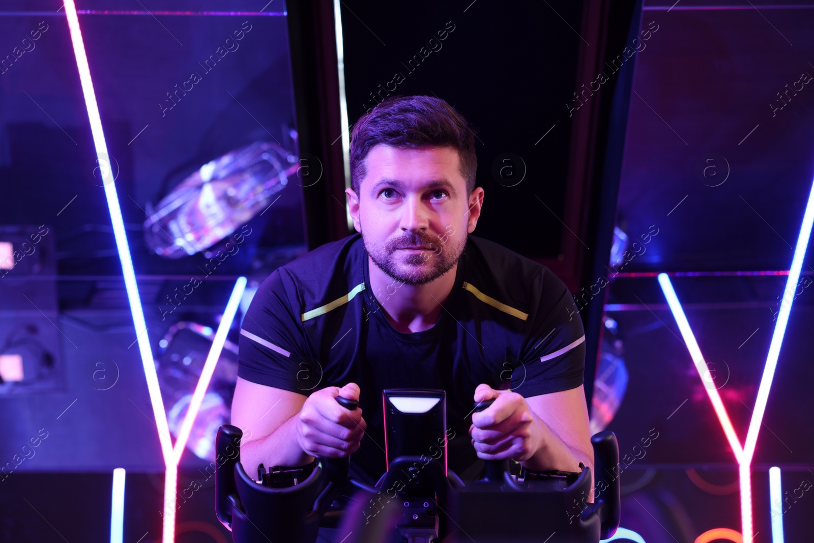 Photo of Man training on exercise bike in fitness club