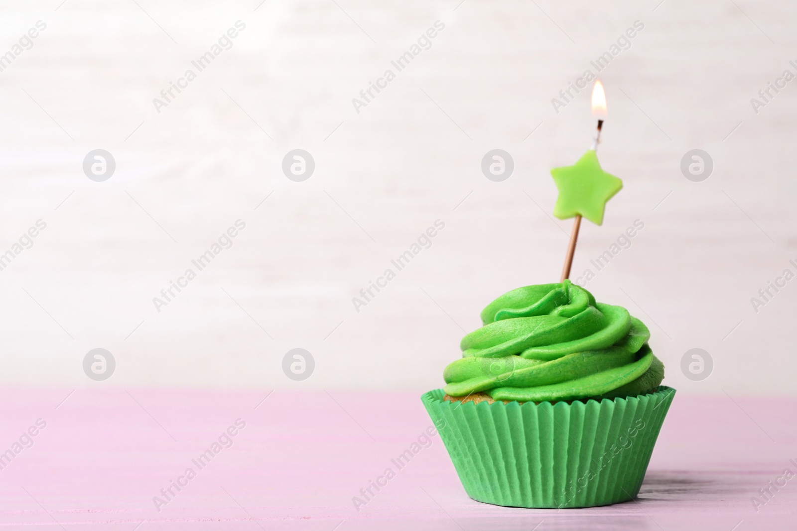 Photo of Delicious birthday cupcake with cream and burning candle on pink table. Space for text