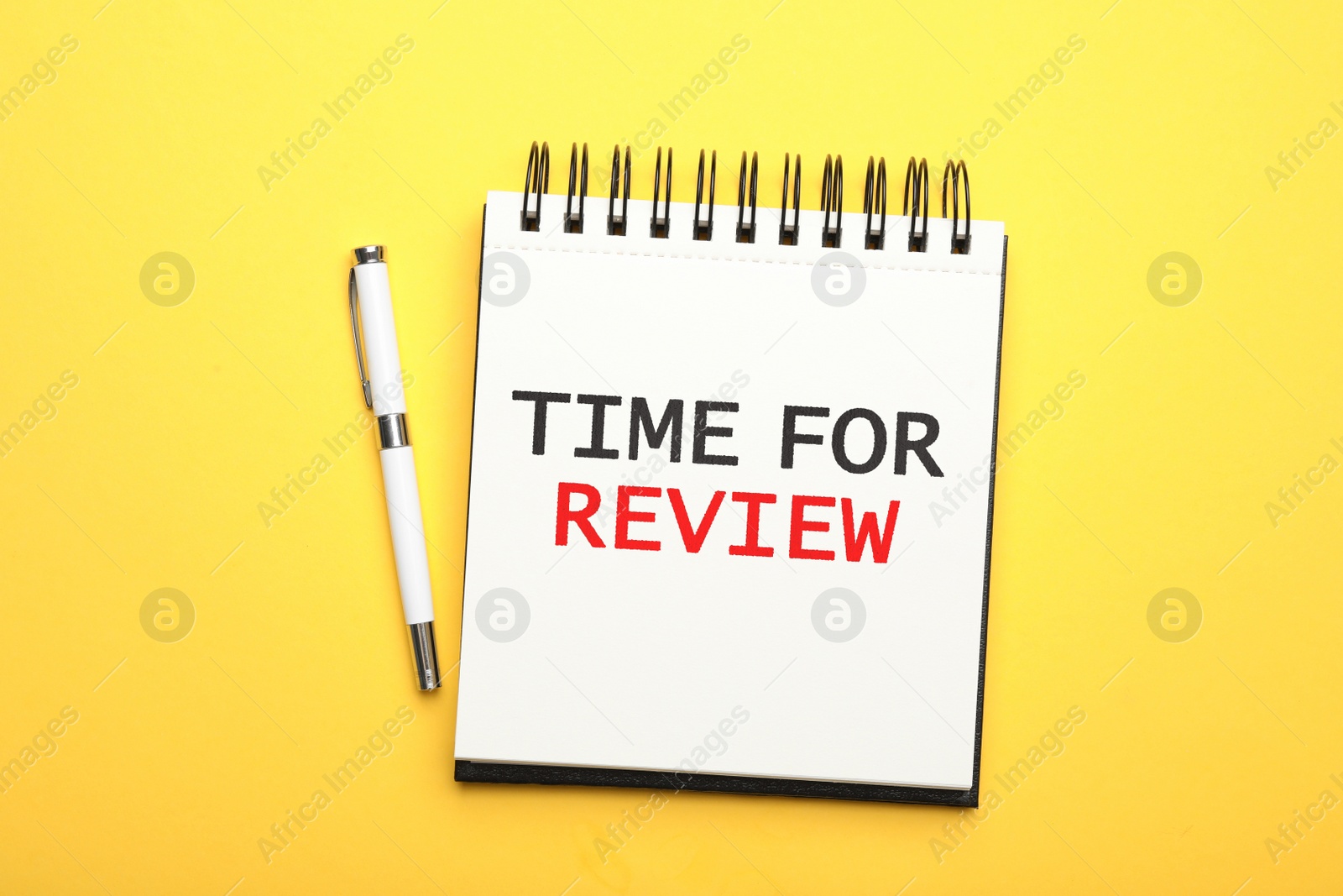 Image of Notepad with phrase Time For Review and pen on yellow background, top view