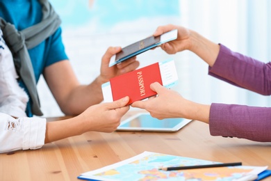 Photo of Female manager giving passports with tickets to clients in travel agency, closeup