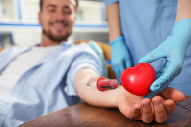 Young man making blood donation in hospital, focus on hands