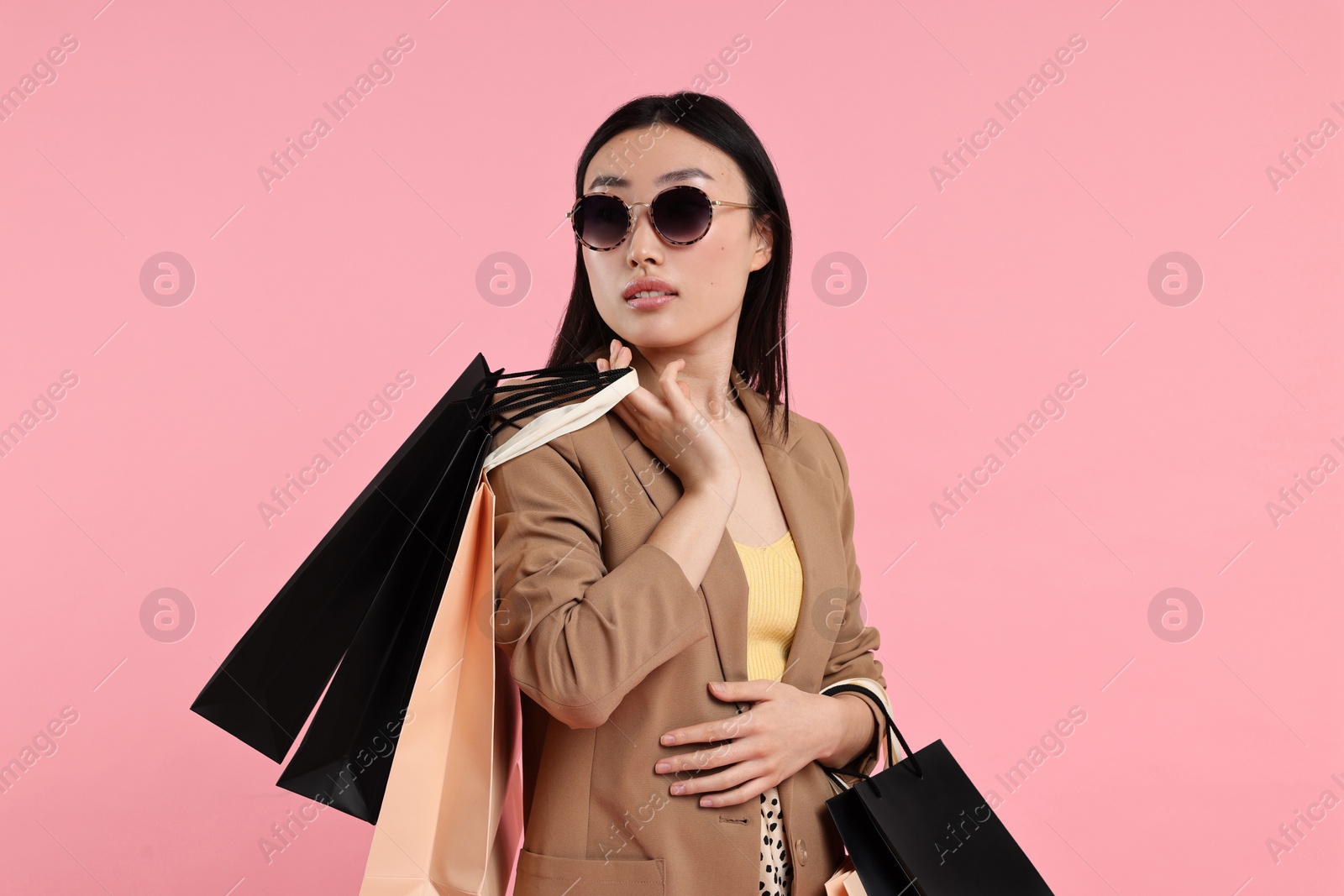 Photo of Beautiful woman with shopping bags on pink background