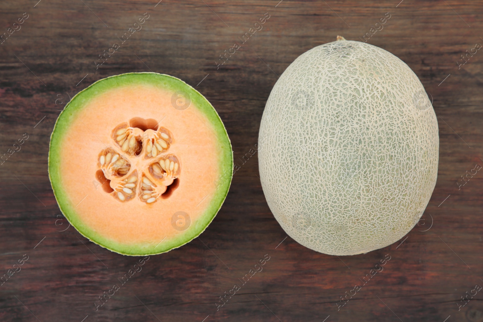 Photo of Whole and cut fresh ripe melons on wooden table, flat lay