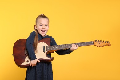 Photo of Happy girl with electric guitar on yellow background. Space for text