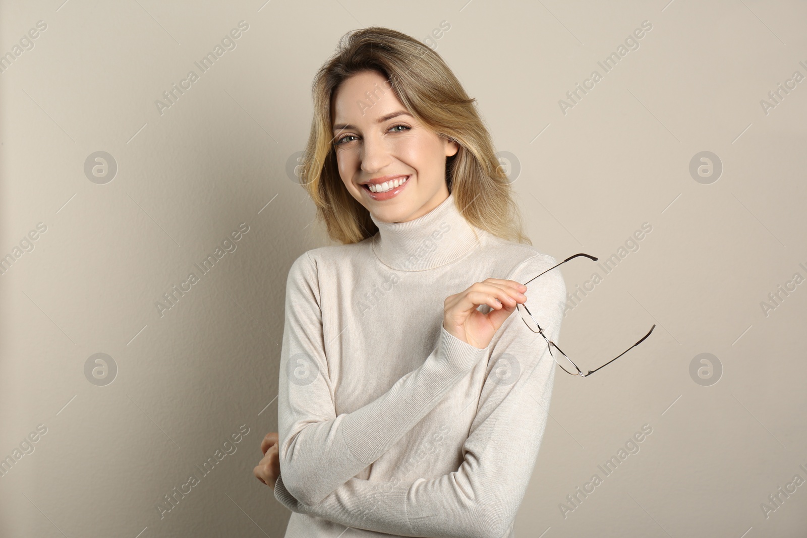 Photo of Portrait of happy young woman with beautiful blonde hair and charming smile on beige background