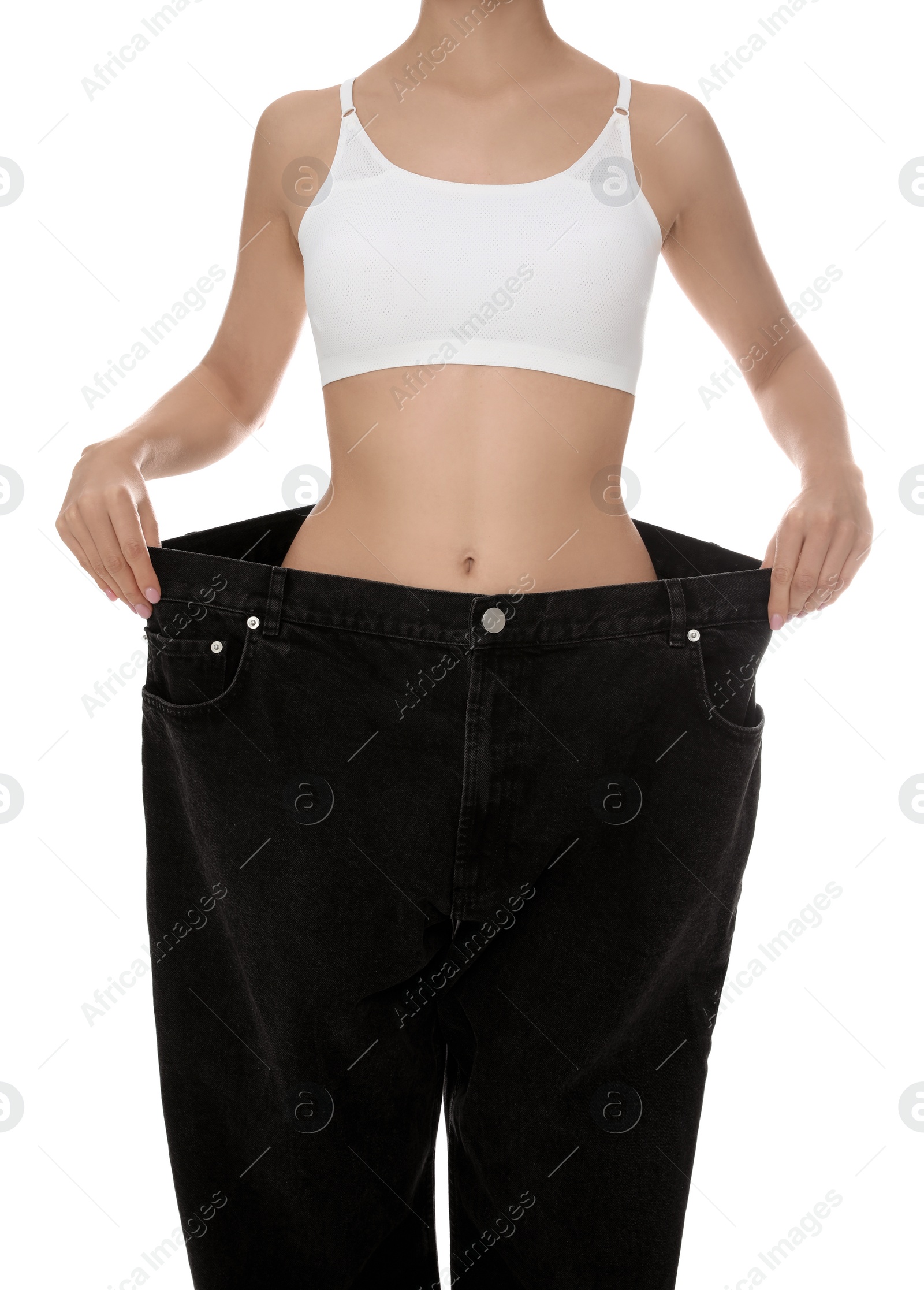 Photo of Young woman wearing big jeans after weight loss on white background, closeup