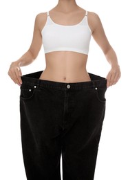 Young woman wearing big jeans after weight loss on white background, closeup