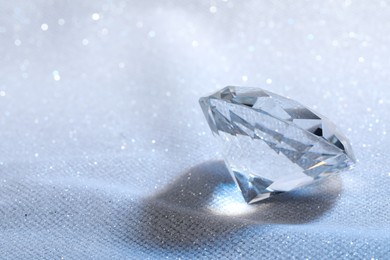 Beautiful dazzling diamond on white glitter fabric, closeup. Space for text