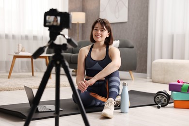 Photo of Happy sports blogger recording fitness lesson with camera at home