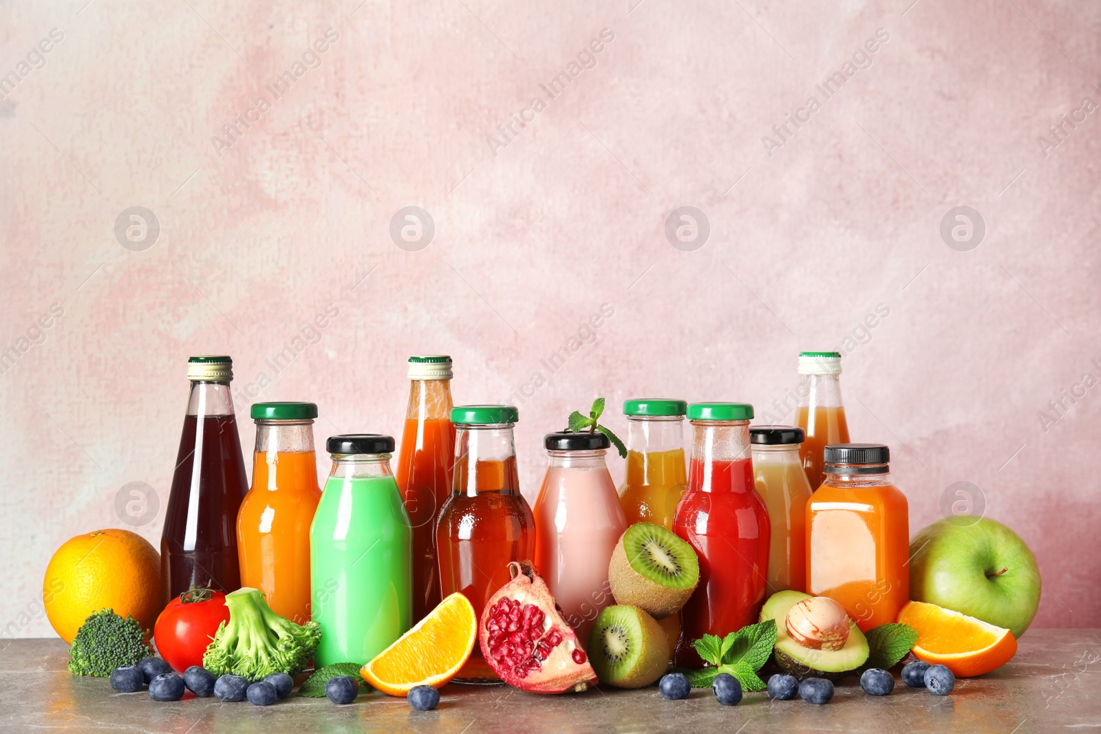 Photo of Bottles with different drinks and ingredients on table against color background