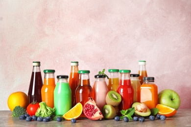 Photo of Bottles with different drinks and ingredients on table against color background