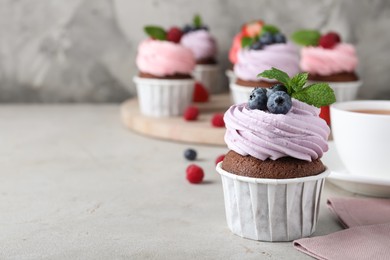 Delicious cupcake with cream and blueberries on light grey table, space for text