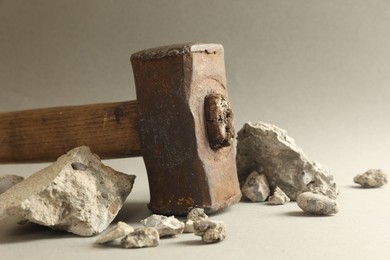 One sledgehammer and pieces of broken stones on grey background, closeup