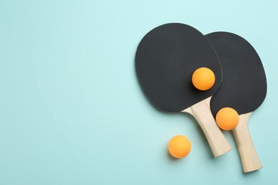Photo of Ping pong rackets and balls on turquoise background, flat lay. Space for text
