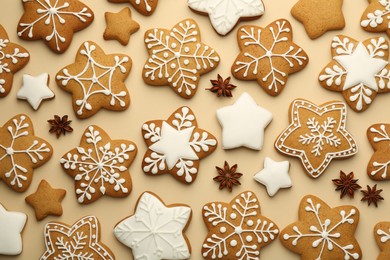 Photo of Tasty Christmas cookies with icing and anise stars on beige background, flat lay