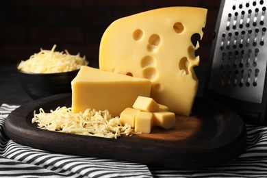 Photo of Grated, cut cheese and grater on table, closeup