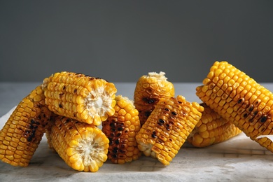 Photo of Grilled corn cobs on table against gray background