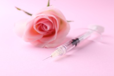Photo of Cosmetology. Medical syringe and rose flower on pink background, closeup