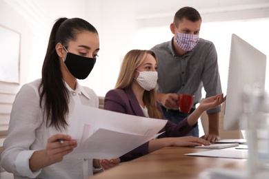 Photo of Coworkers with masks in office. Protective measure during COVID-19 pandemic