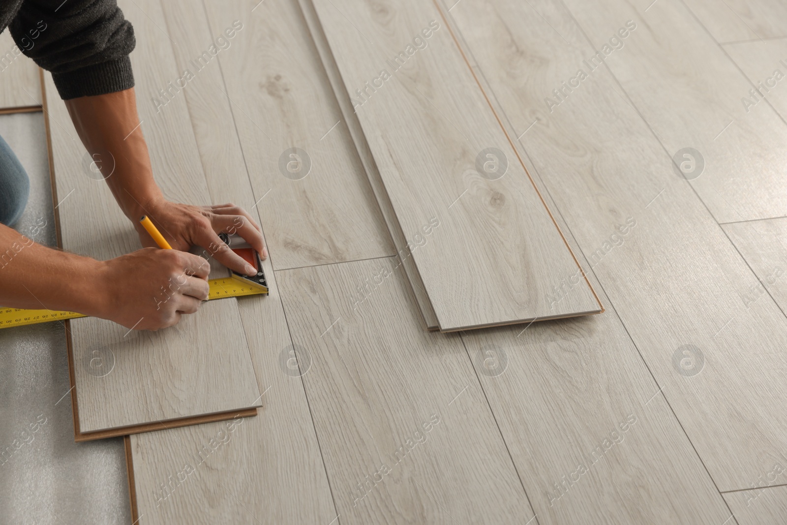 Photo of Worker installing new laminate flooring in room, closeup