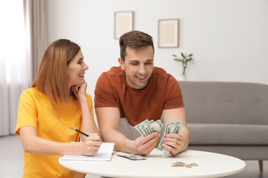 Photo of Couple counting money at table in living room