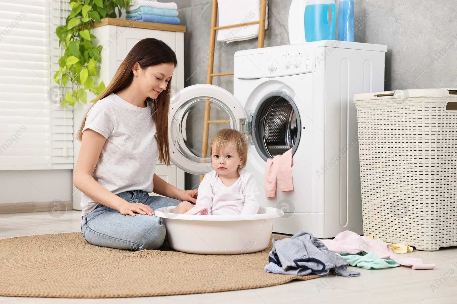 Photo of Mother with her daughter washing baby clothes in bathroom