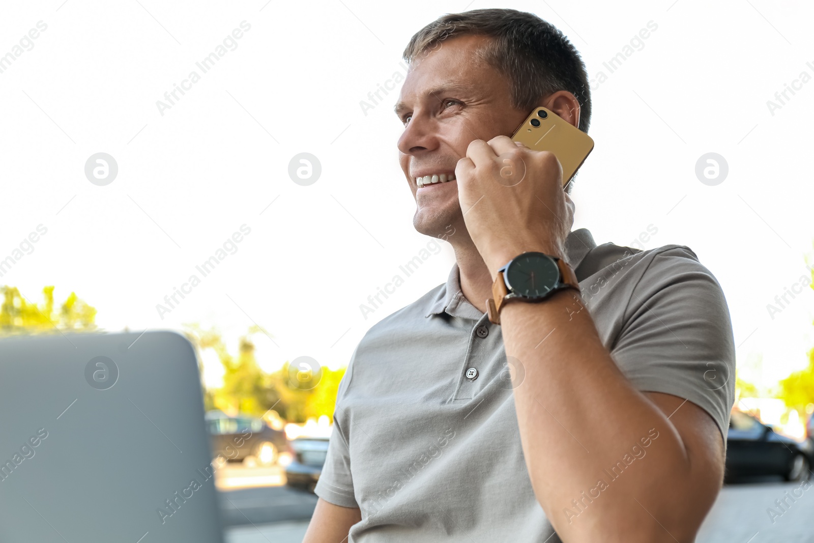 Photo of Man talking on smartphone in outdoor cafe
