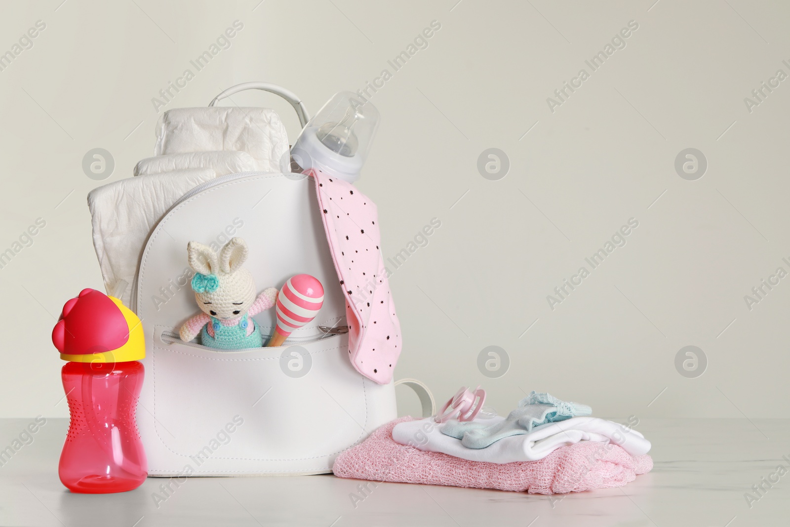 Photo of Mother's backpack with baby's stuff on light grey background. Space for text