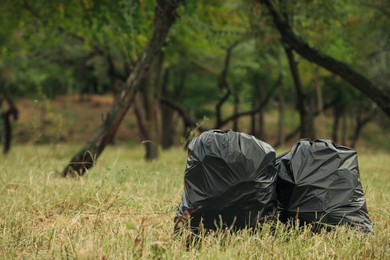 Photo of Trash bags full of garbage outdoors. Space for text