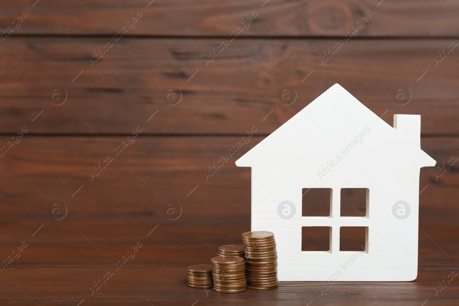 Photo of House model and coins on wooden background. Space for text