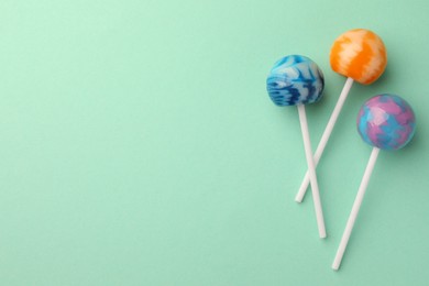 Photo of Tasty lollipops on turquoise background, flat lay. Space for text