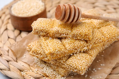 Photo of Delicious sesame kozinaki bars and wooden dipper on wicker mat, closeup