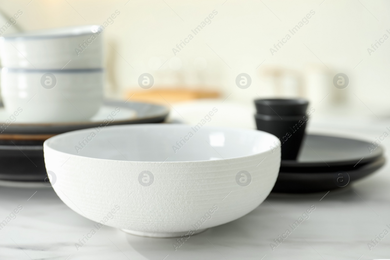 Photo of Clean ceramic bowl on white marble table in kitchen, closeup