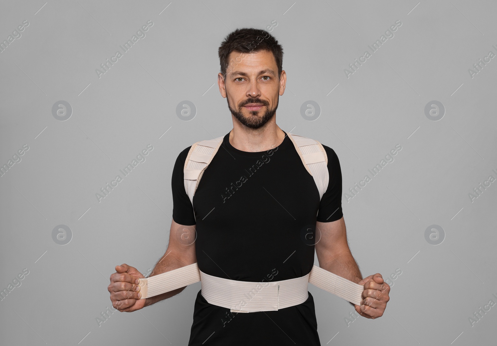 Photo of Handsome man with orthopedic corset on grey background